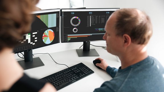 Ein interdisziplinärer Austausch zwischen einer Radiologin und einem Investigator bei der Analyse des multizentrischen Studienfortschritts und quantitativer Bilddaten auf einem mint Lesion Dashboard.