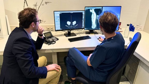 This picture shows two men (one is a doctor) looking at a medical image within the program mint Lesion™