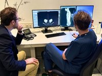 This picture shows two men (one is a doctor) looking at a medical image within the program mint Lesion™