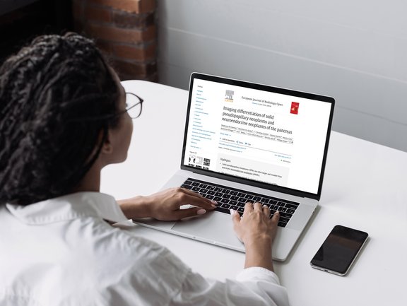 Doctor reading study on pancreas on laptop