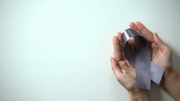 Zwei Hände, die in ihrer Handfläche eine graue Krebsschleife halten