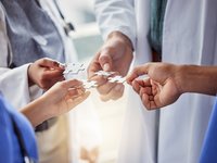 Doctors holding up puzzle pieces; representing working together