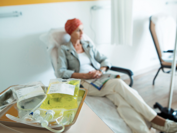 A picture of a cancer patient on a couch, with two infusion bags in the foreground