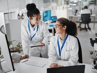 Two female medical researchers talking about their research project