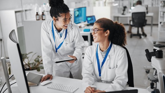 Two female medical researchers talking about their research project
