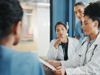 Medical personnel looking at a technical device to discuss diagnostic guidelines